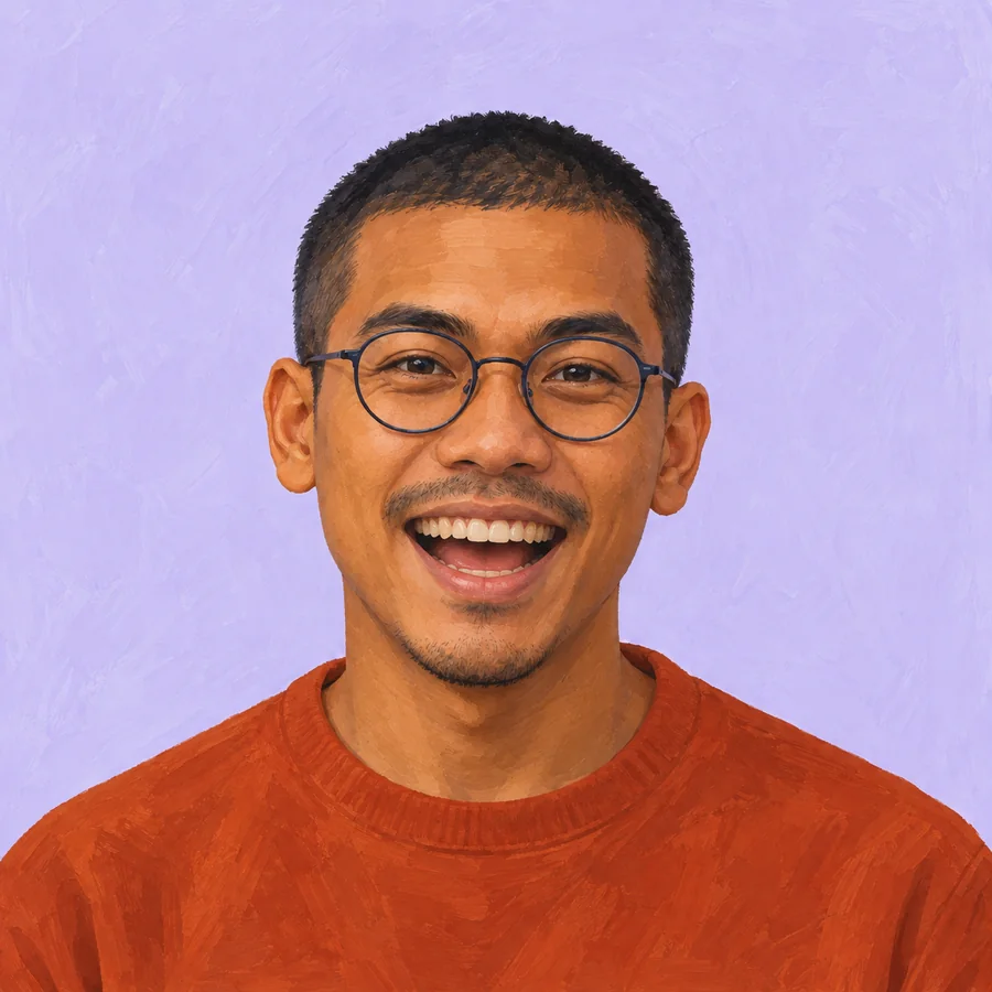 The same glasses-wearing man smiling widely in his burnt-orange crewneck